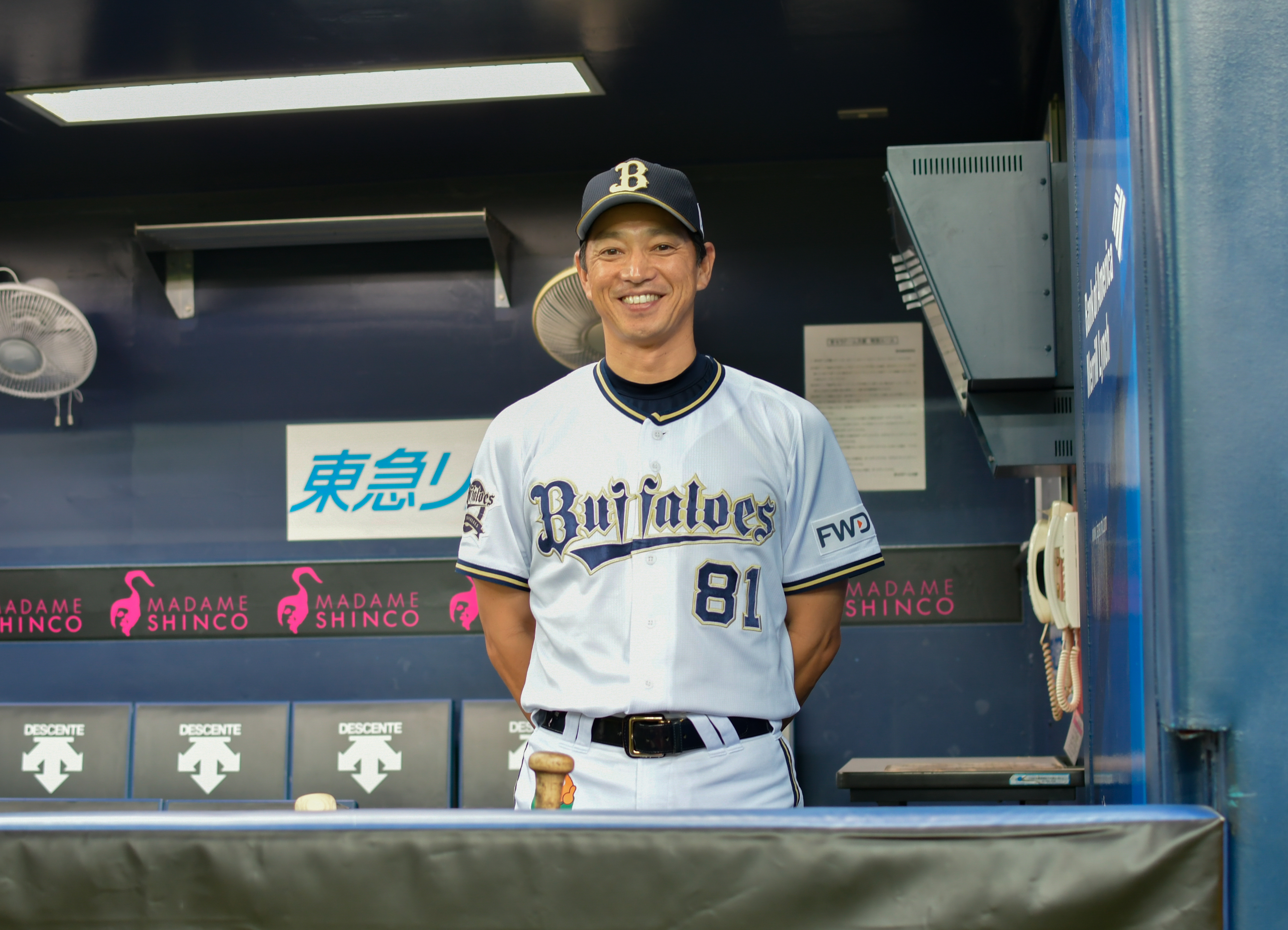 オリックス・バファローズ一軍野手総合コーチ兼打撃コーチを務める田口壮さんがベンチで笑顔で立っている所